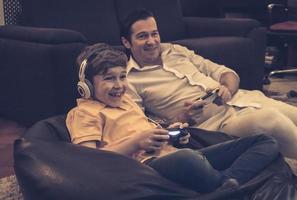 hijo y padre alegres jugando videojuegos en casa. foto