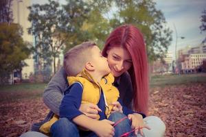 hijo pequeño besando a su madre en la mejilla. foto