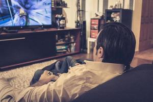 Rear view of father playing video games with his son at home. photo
