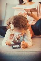 Smiling girl using smart phone while relaxing on the sofa. photo