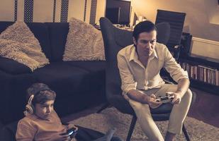 Father and son playing video games while relaxing at home. photo