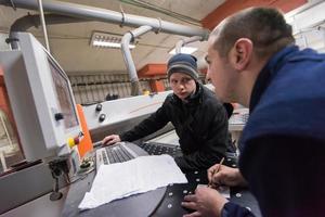 carpenters calculating and programming a cnc wood working machine photo