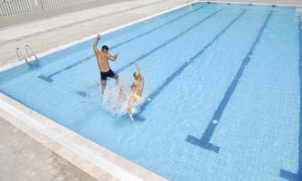 familia joven feliz divertirse en la piscina foto