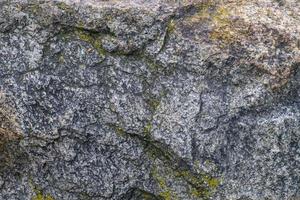 Raw gray granite rock texture background. Fragment of natural stone wall photo