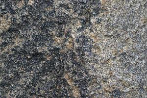 Fondo de textura de roca de granito gris crudo. fragmento de muro de piedra natural foto