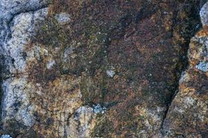 Fondo de textura de roca de granito gris crudo. fragmento de muro de piedra natural foto