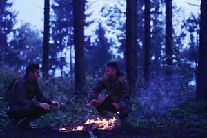 soldiers resting by fire in forest photo