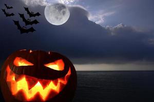 el fondo oscuro de la noche en el mar con calabaza y luna llena halloween. concepto de fondo de halloween. foto
