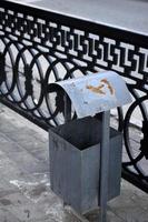 un basurero de hierro en una gran ciudad en verano. cubo de basura en la calle de la ciudad. foto