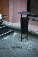 An iron garbage can in a big city in summer. Dumpster bucket on the street of the city. photo