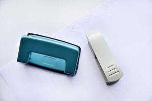 A white stapler and a green hole punch on a white background. Stationery on a white background. photo