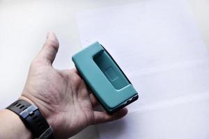 Green hole punch in hand on a white background. Stationery close-up. photo