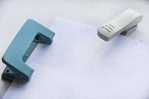 A white stapler and a green hole punch on a white background. Stationery on a white background. photo