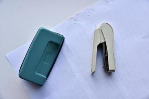 A white stapler and a green hole punch on a white background. Stationery on a white background. photo