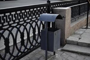 un basurero de hierro en una gran ciudad en verano. cubo de basura en la calle de la ciudad. foto