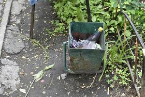 Dirty trash can in the yard. A garbage bin in the yard of the house in summer. photo