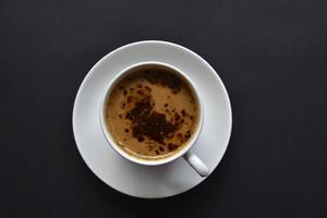 Delicious coffee in a porcelain cup with a saucer and coffee beans. Coffee in a cup and beans on a black background. photo