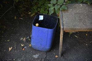 Dirty trash can in the yard. A garbage bin in the yard of the house in summer. photo