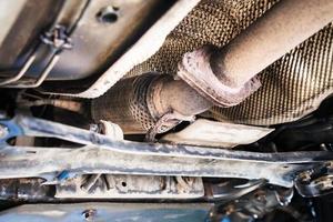 bottom view of broken corrugation muffler on car photo