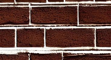 A wall of old, cracked bricks, with a weathered and faded surface. Restored brickwork of an old house. photo