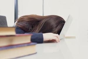 el cabello largo de una mujer joven se queda dormido en el escritorio con una laptop foto