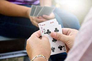 Paper cards number 5 holding in hands of woman who sitting and playing card with friend, soft and selective focus, freetimes and hobby activity at home concept. photo