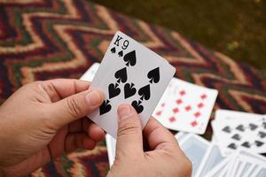 Paper cards number 5 holding in hands of woman who sitting and playing card with friend, soft and selective focus, freetimes and hobby activity at home concept. photo