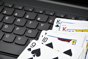 Paper cards on blank laptop keyboard, soft and selective focus, concept for playing cards online with other people at home and recreational activity. photo