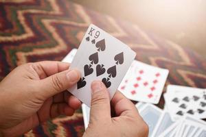 Paper cards number 9 and King holding in hands of woman who sitting and playing card with friend, soft and selective focus, freetimes and hobby activity at home concept. photo