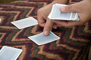 Paper cards number 5 holding in hands of woman who sitting and playing card with friend, soft and selective focus, freetimes and hobby activity at home concept. photo