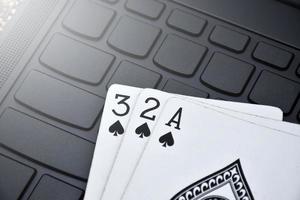 Poker paper cards on blank laptop keyboard, soft and selective focus, concept for playing cards online with other people at home and recreational activity. photo