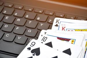 Paper cards on blank laptop keyboard, soft and selective focus, concept for playing cards online with other people at home and recreational activity. photo