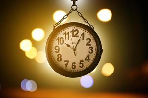 Closeup vintage hanging clock, blurred street light bokeh background, soft and selective focus on clock. photo