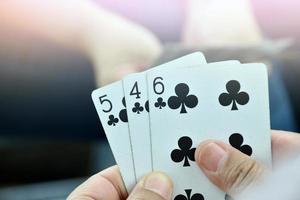 Paper cards number 5,4,6 holding in hands of woman who sitting and playing card with friend, soft and selective focus, freetimes and hobby activity at home concept. photo