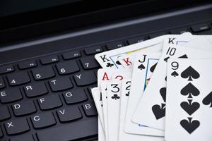 Paper cards on blank laptop keyboard, soft and selective focus, concept for playing cards online with other people at home and recreational activity. photo