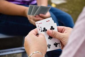 Paper cards number 5 holding in hands of woman who sitting and playing card with friend, soft and selective focus, freetimes and hobby activity at home concept. photo