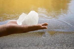 White alum bar holding in hand with cloudy water, concept for using alum to sway or swing the cloudy water to be clean and clear before using it in human daily life, soft and selective focus. photo