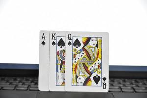 Paper cards on blank laptop keyboard, soft and selective focus, concept for playing cards online with other people at home and recreational activity. photo