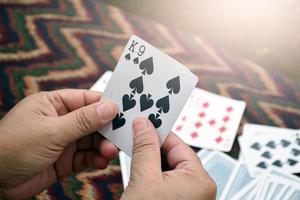 Paper cards number 9 and King holding in hands of woman who sitting and playing card with friend, soft and selective focus, freetimes and hobby activity at home concept. photo