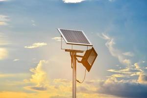 mini panel solar o fotovoltaico instalado en un poste de metal con luz de inundación, fondo borroso y azul cielo, concepto para utilizar la energía natural del sol en la vida diaria de los humanos. foto