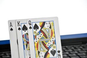 Paper cards on blank laptop keyboard, soft and selective focus, concept for playing cards online with other people at home and recreational activity. photo