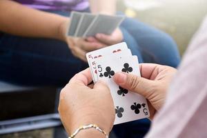 Paper cards number 5 holding in hands of woman who sitting and playing card with friend, soft and selective focus, freetimes and hobby activity at home concept. photo