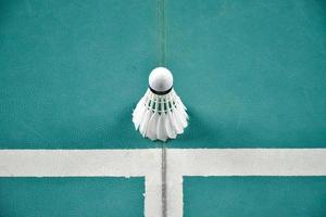 Cream white badminton shuttlecock on green floor in indoor badminton court, blurred badminton background, copy space photo