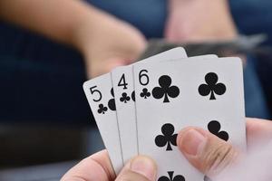 Paper cards number 5 holding in hands of woman who sitting and playing card with friend, soft and selective focus, freetimes and hobby activity at home concept. photo