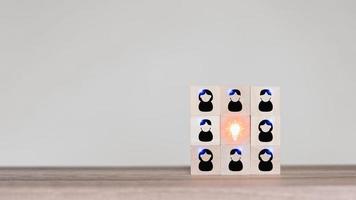 Team thinking with light bulb creative idea icon on wooden cube block which is placed on a table. Business growth and goal in next year concept. photo