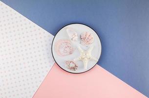 Plate with seashells on color paper background photo