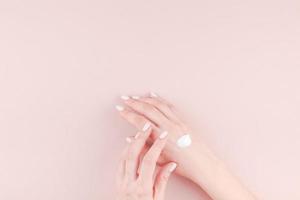 Woman moisturizing her hand with cosmetic cream photo