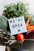 Text We're open and Fresh green and vegetables box photo