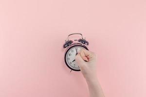 Female hand with alarm clock. Morning concept photo