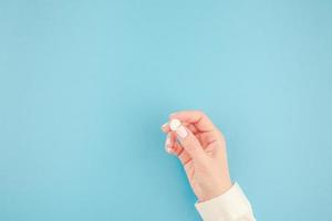 mano femenina sosteniendo una pastilla blanca foto